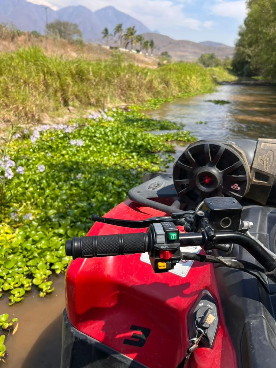 Cuatrimoto roja junto al río en la ruta San Miguel